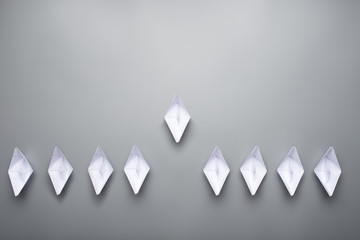 Nine paper made origami boats over grey background