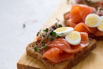 Toasts with smoked salmon garnished with quail egg and radish sprouts