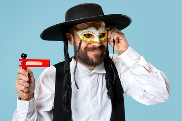 Portrait of a young orthodox Hasdim Jewish man with wooden Grager Ratchet at Jewish festival of Purim at studio. The purim, jewish, festival, holiday, celebration, judaism, pastry, tradition, cookie