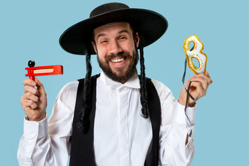 Portrait of a young orthodox Hasdim Jewish man with wooden Grager Ratchet at Jewish festival of...