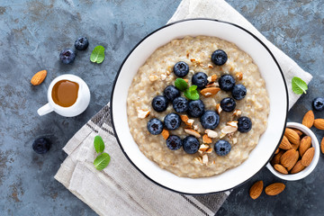 Oatmeal with fresh raw blueberry, almond nuts and honey for breakfast. Healthy vegetarian food. Top view