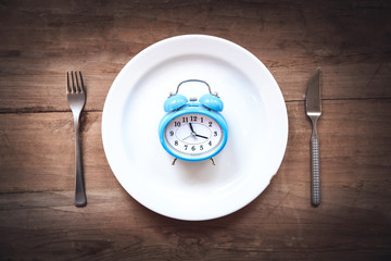 Alarm clock with fork and knife on the table. Time to eat
