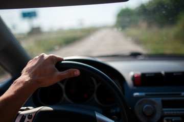 A man driving a car, focus on the left hand held on steering wheel