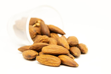 Full of almonds spilled out on white background with copy space.