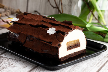 Yule log cake decorated with chocolate leaves on a Christmas table
