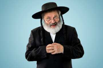 Portrait of old senior orthodox Hasdim Jewish man with wooden Grager Ratchet at Jewish festival of...
