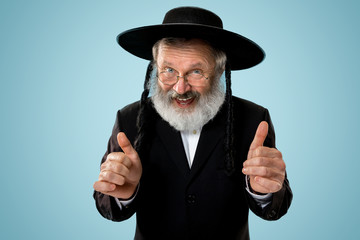 Portrait of old senior orthodox Hasdim Jewish man with wooden Grager Ratchet at Jewish festival of...