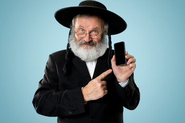 Portrait of old senior orthodox Hasdim Jewish man with mobile phone at Jewish festival of Purim at studio. The purim, jewish, festival, holiday, celebration, judaism, tradition, business