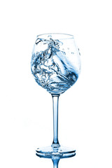 Blue splashes of clean water in the wine glass. A spray of water. Drinking water.