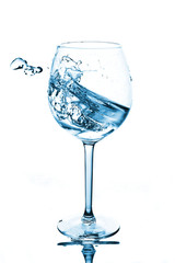 Blue splashes of clean water in the wine glass. A spray of water. Drinking water.