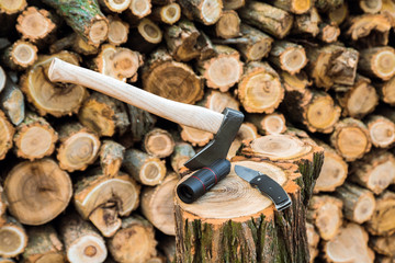 axe, monocle and jackknife case on the stump, firewoods on the background