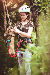Happy school girl enjoying activity in a climbing adventure park on a summer day
