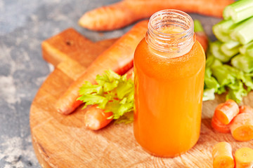 Fresh green celery, juice in bottle on background near the carrots. 