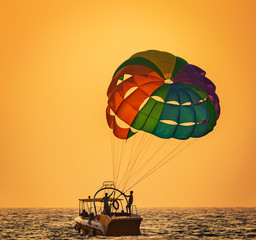 amazing shot at sunset of Parasailing water amusement - flying on a parachute behind a boat on a summer holiday by the sea in the resort Baga beach Goa India India watersports