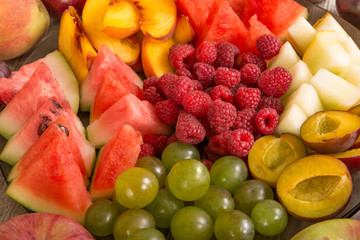 Fruit mix. Peach, grapes, apple, watermelon, melon, raspberry, plum. Juicy and ripe pieces of fruit close-up.