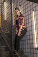 Beautiful and sexy girl posing for a photographer on the black iron stairs with lamps in a cafe.