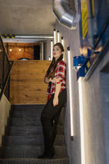 Beautiful and sexy girl posing for a photographer on the black iron stairs with lamps in a cafe.