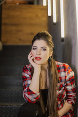 Beautiful and sexy girl posing for a photographer on the black iron stairs with lamps in a cafe.