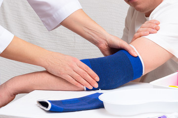doctor helps the patient to use bandage on the elbow