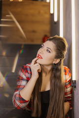 Beautiful and sexy girl posing for a photographer on the black iron stairs with lamps in a cafe.