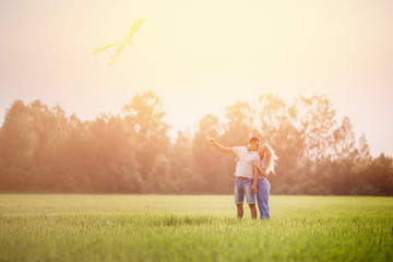 Pair of man and woman lovers launch flying kite symbol of freedom in field at sunset. Concept family, first kiss