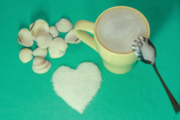 cup of cappuccino and heart shape in sugar on turquoise fabric background
