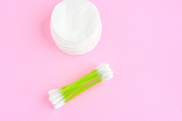 Fototapeta na wymiar Clean cotton stack of disk for beauty hygiene with selective focus and individual ear sticks with sterile softness applicator on pink neutral background. Ear swabs and face sponges for health