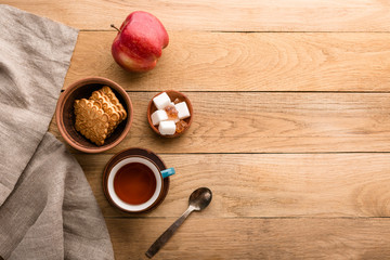 Tea, apple, cookies and sugar on a brown wooden table, breakfast, rustic style, snack, top view, copy space