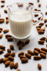 Almond milk in a glass surrounded by organic almonds