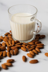 Almond milk in a glass surrounded by organic almonds