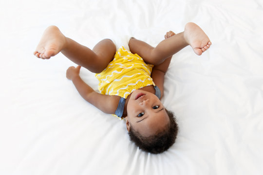 Toddler girl making funny pose upside down on bed