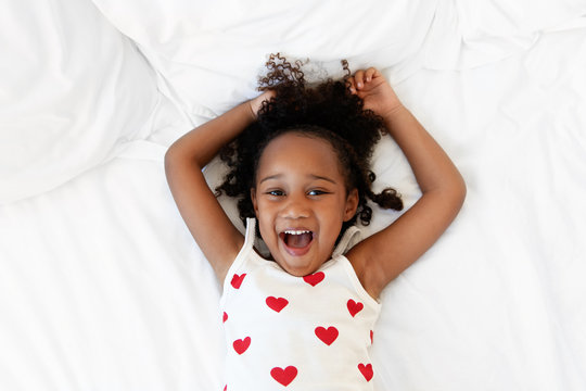 Happy girl lying on back holding arms above head