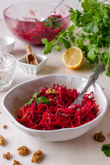 Healthy raw vegan beetroot salad with carrot and walnuts in a bowl on white wooden table. Natural organic food concept. Healthy diet