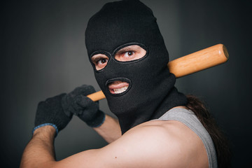 Bandit, the criminal in a black mask and in a gray T-shirt with a painless bat. Robber with a...