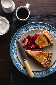 Slice of cherry pie with coffee and cream