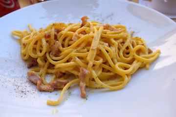 A classic pasta carbonara served outside in a pizzaria restaurant in Lucca, Italy