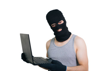 A thief in a black mask stole a laptop. A man in a balaclava and with a computer in hands on a...