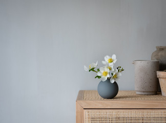 weiße Blume  in grauer Vase auf einem Schrank im skandinavischen Design