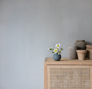Blumenvase mit Fr&uuml;hlingsblumen auf Schrank mit nat&uuml;rlicher Dekoration