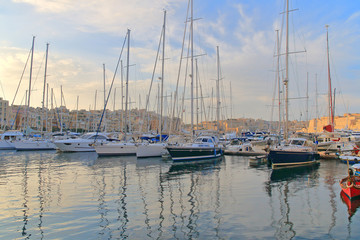 Fototapeta na wymiar Sunset over moored yachts in a quiet bay in Malta.