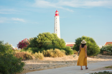 Tourist woman walking under the lighthouse of Farol Island in Formosa Estuary, Algarve, Portugal.