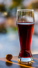 The glass in which is filling the red wine near the nut and blue background in blur with bokeh