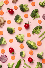 Colorful pattern of tomatoes, broccoli, carrots, ginger and onion on a pink background