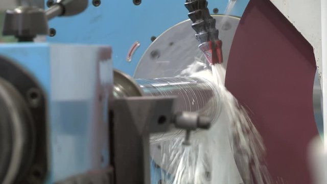 Finishing metal working on high precision grinding machine in workshop. Grinding work. Round grinding - machining of external cylindrical and conical surfaces of parts.