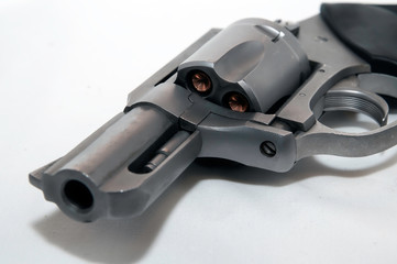 A close up of a stainless snub nose 357 magnum revolver on it's side loaded with hollow point bullets on a white background