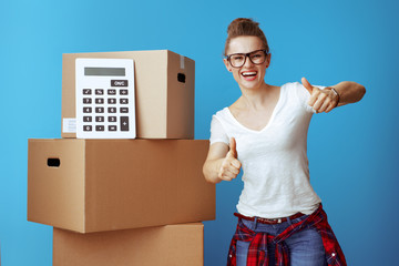woman showing thumbs up near cardboard box with calculator