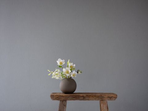 Kleine runde Keramikvase auf einem alten Vintage-Schemel mit Blumen im Frühling