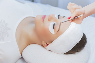 Beautiful young girl with long eyelashes tweezing her eyebrows in a beauty salon. Eyebrow Correction. Beauty Concept. Permanent Makeup. Microblading brow. Beautician Doing brows Tattooing. Treatment.