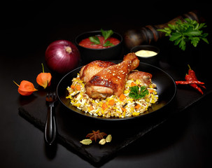 grilled chicken legs with sesame and rice on a black background.