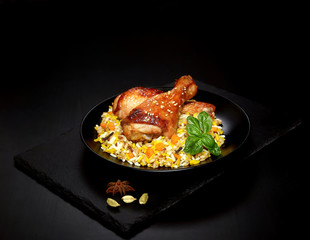grilled chicken legs with sesame and rice on a black background.